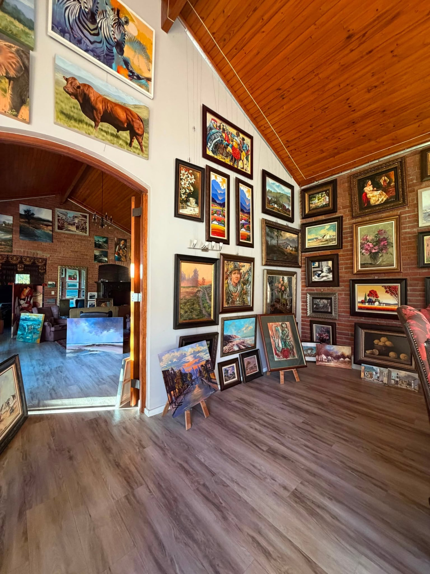A wide view of Kunssinnig Gallery, paintings hung across the walls of the room