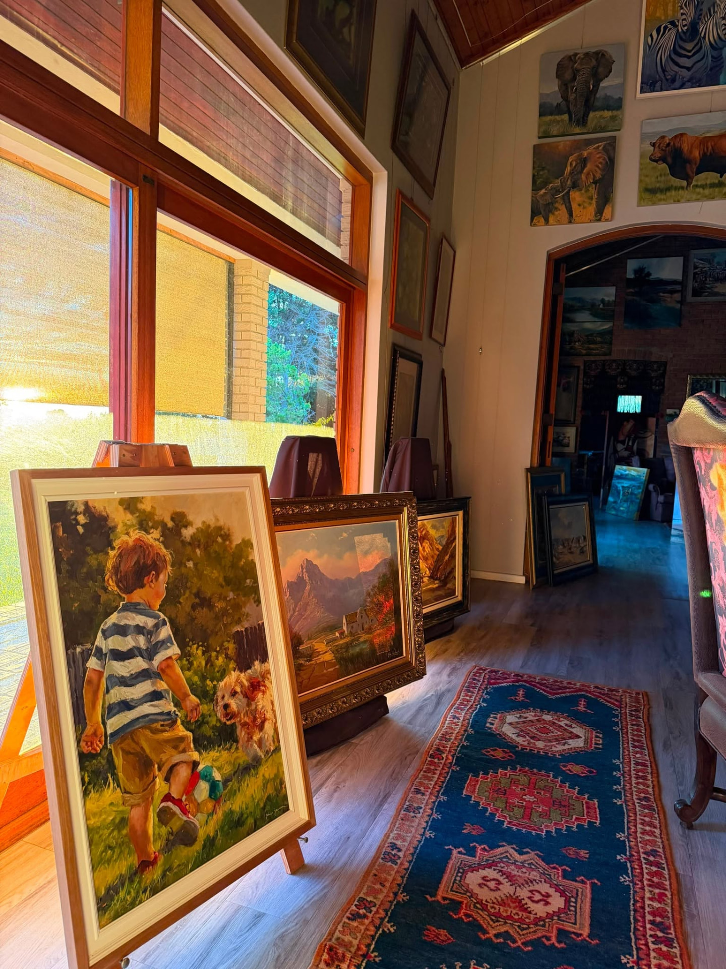 A room at Kunssinnig Gallery hung wall to wall with framed South African paintings